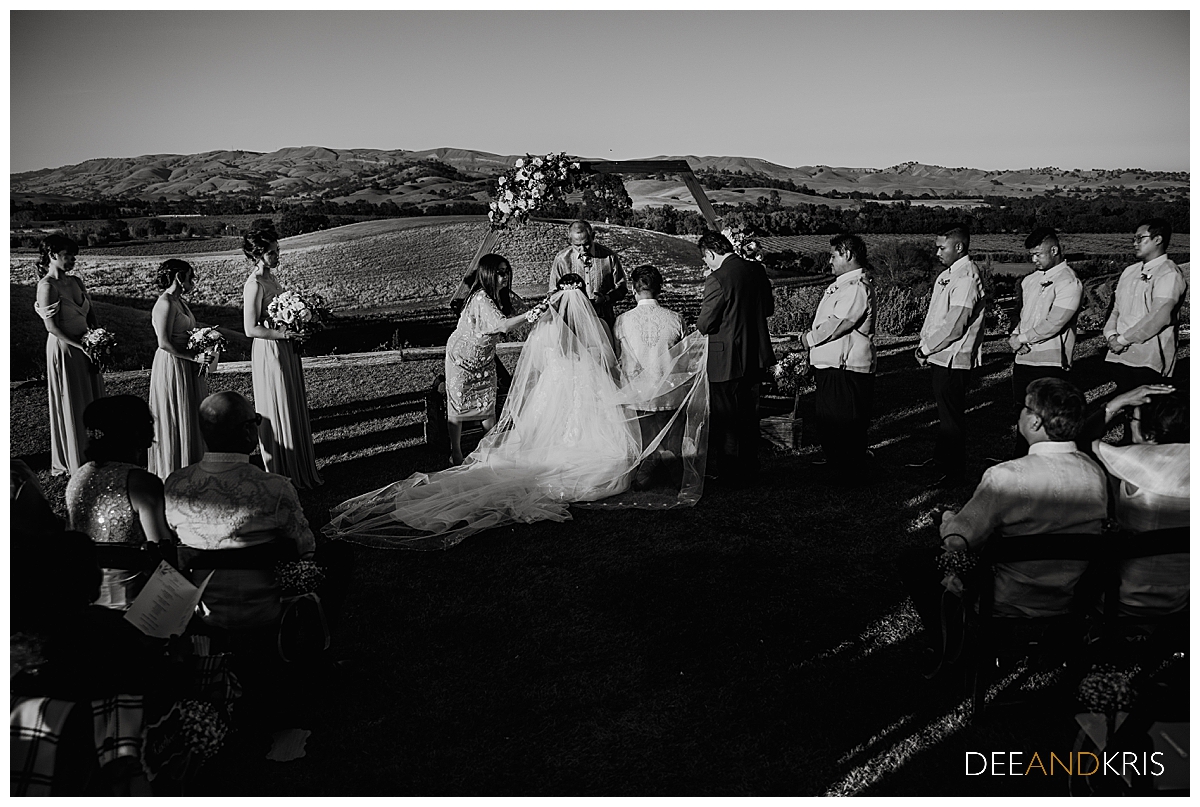 One black and white image of bride and groom kneeling in prayer.