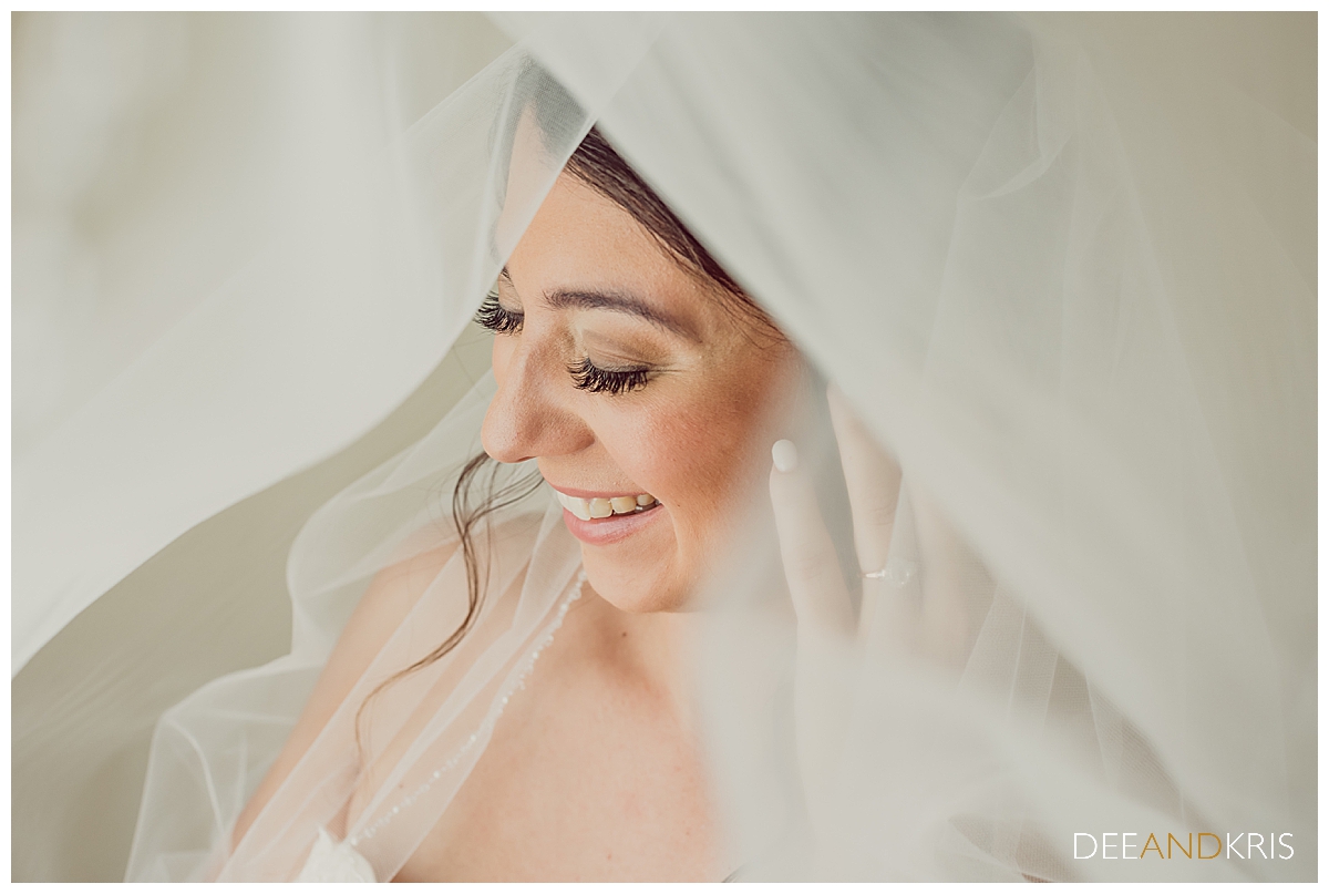 One image of bride enveloped in her veil and laughing.
