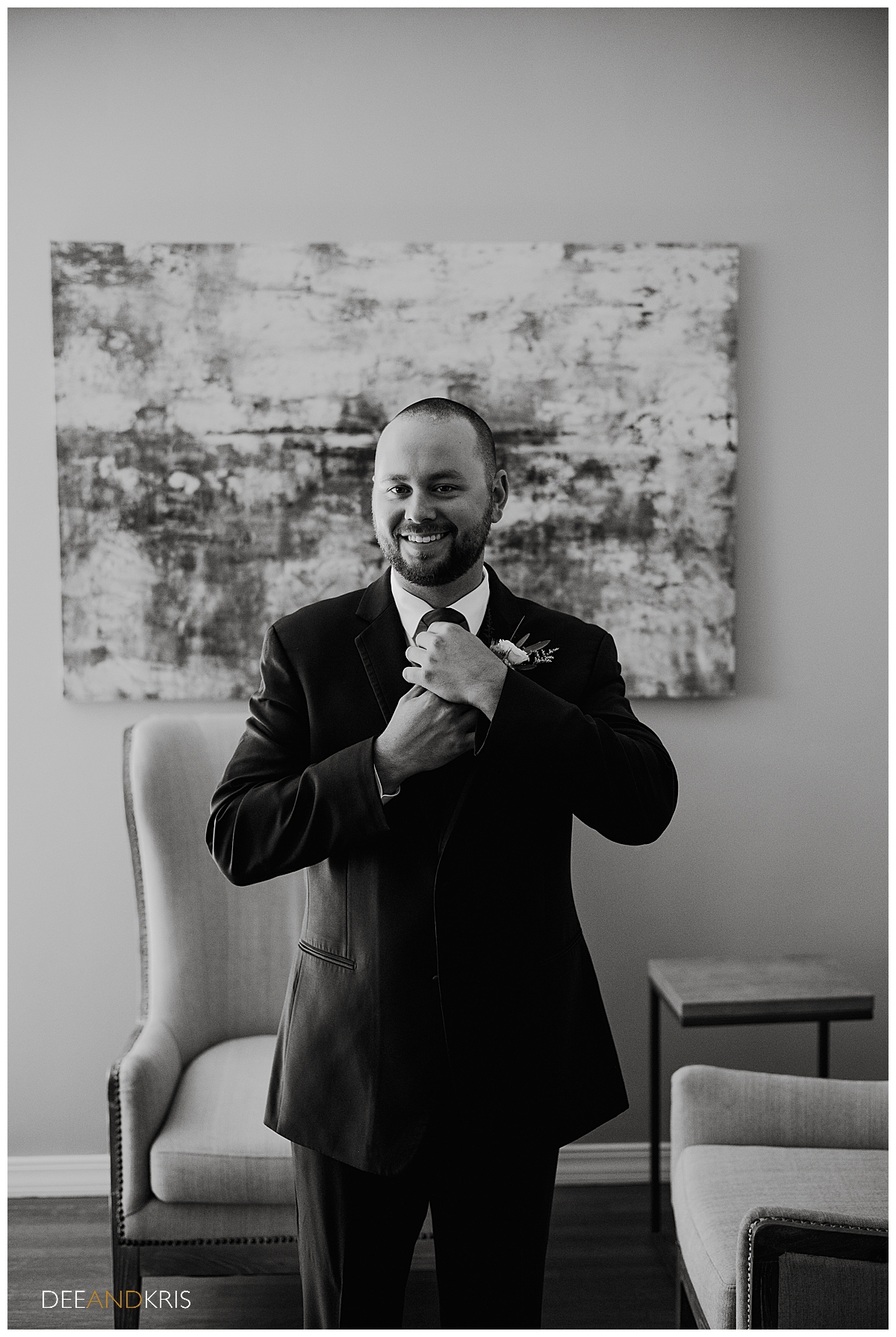 One black and white image of the groom looking at the camera while adjusting his tie.