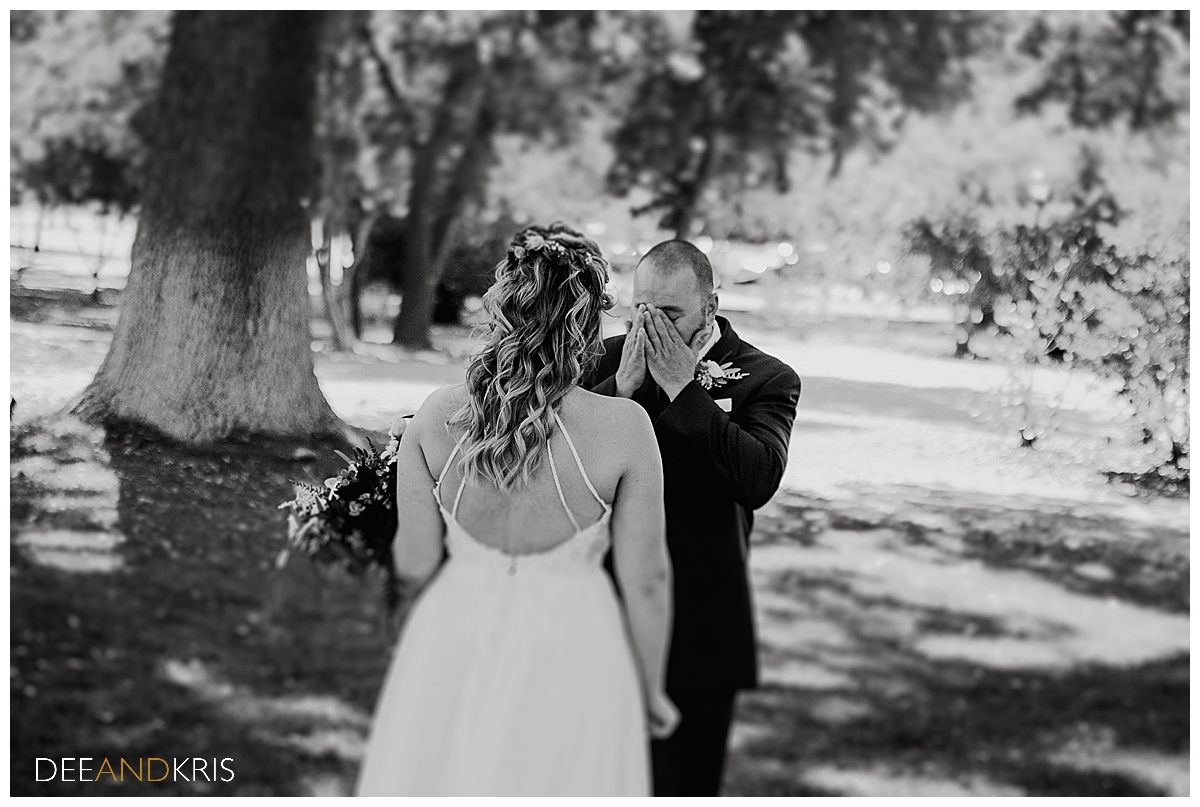 One black and white image of the groom wiping away tears as he sees the bride.