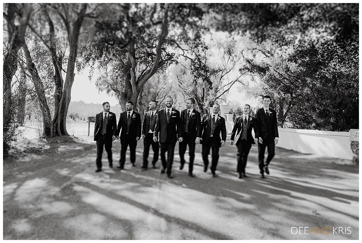 One black and white image of the groom and groomsmen walking toward the camera.