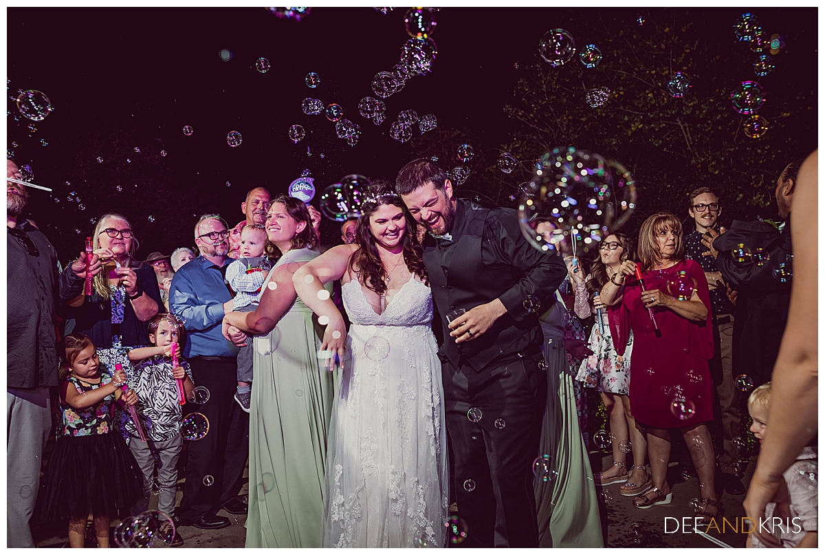 One image of bride and groom dancing while surrounded by guests and bubbles.