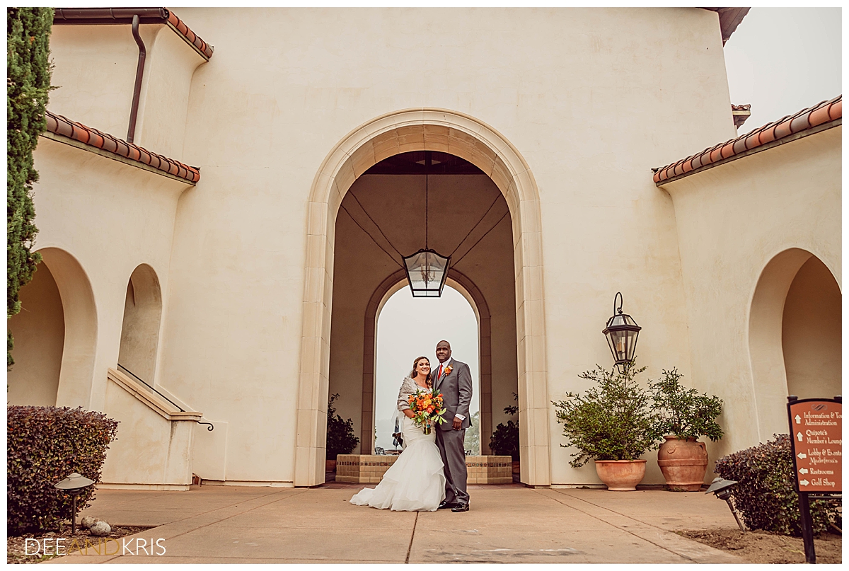 Single image of couple standing together in front of arched entrance,