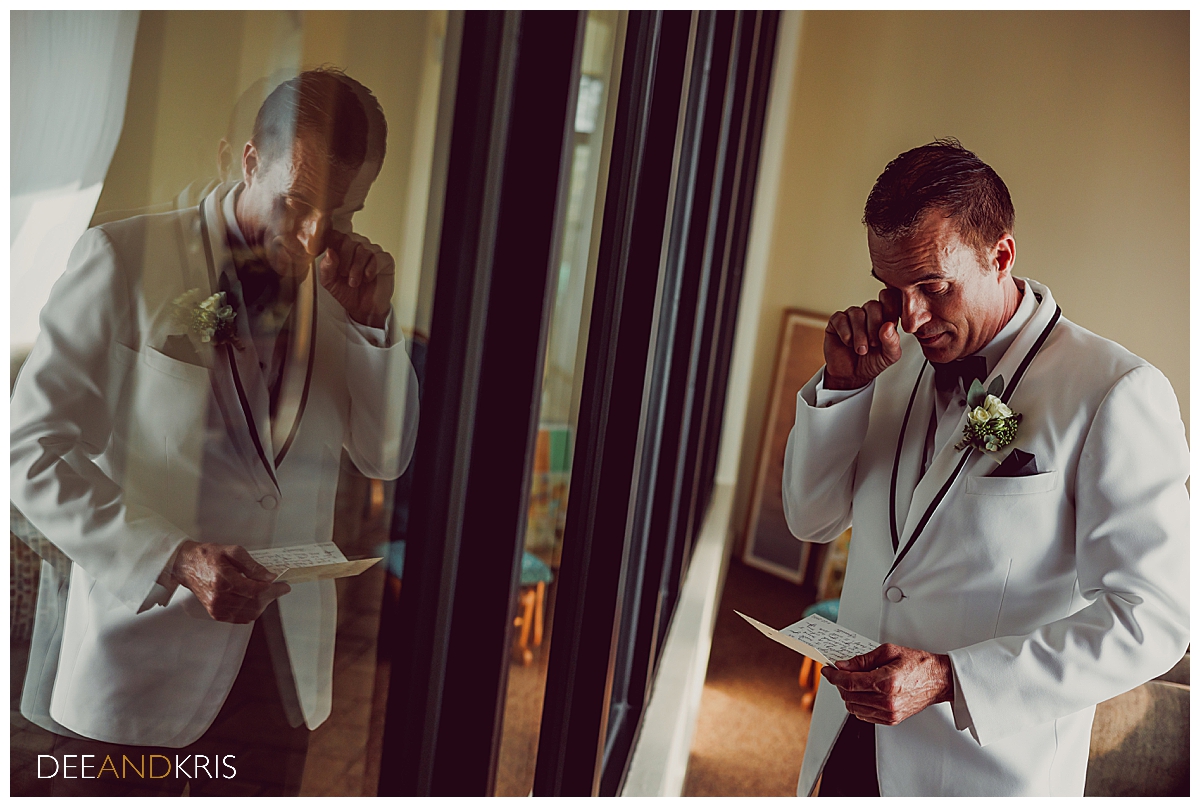 Single image of groom wiping away tears as he reads bride's letter to him.