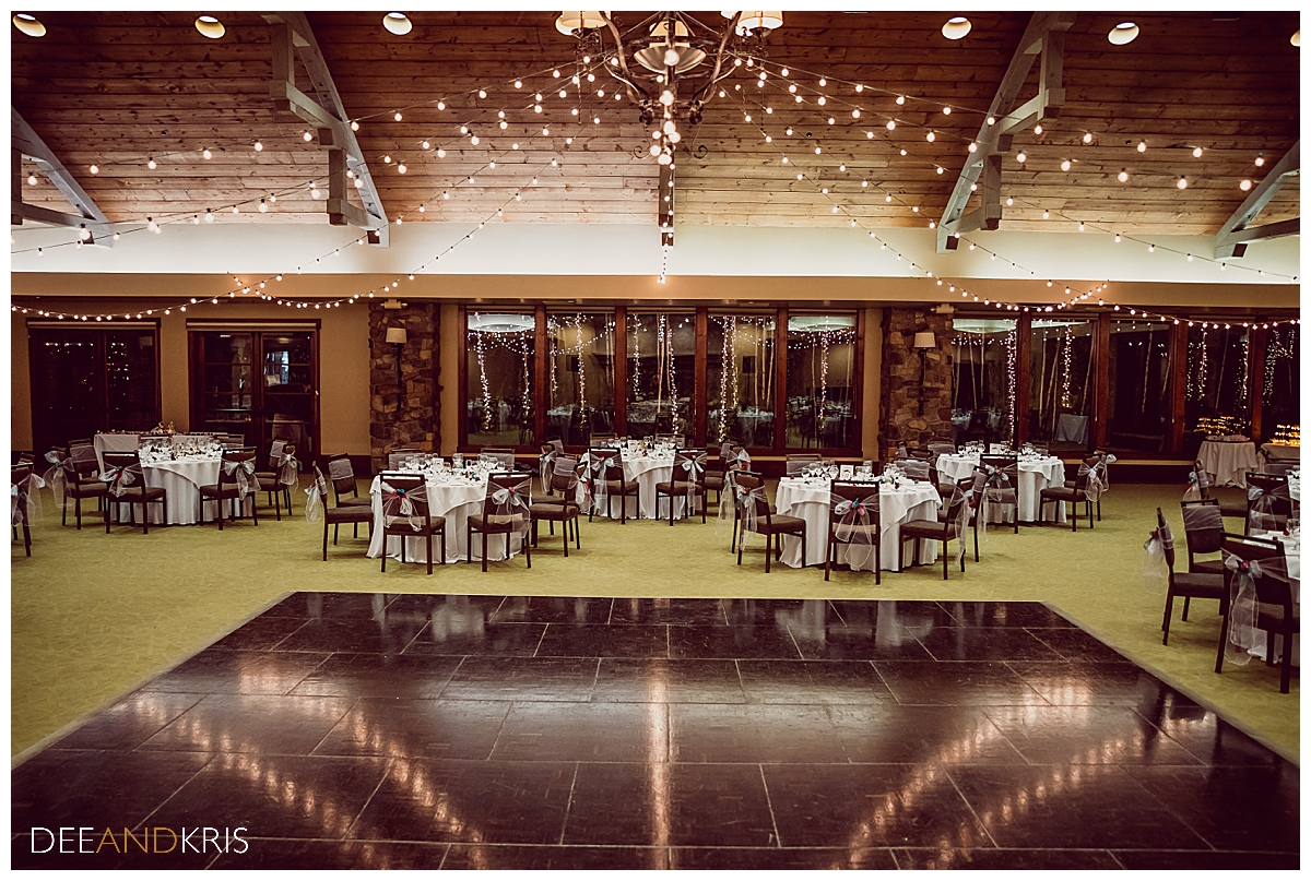 Single image of venue reception seating and dancefloor with reflection of market lighting hanging from ceiling.